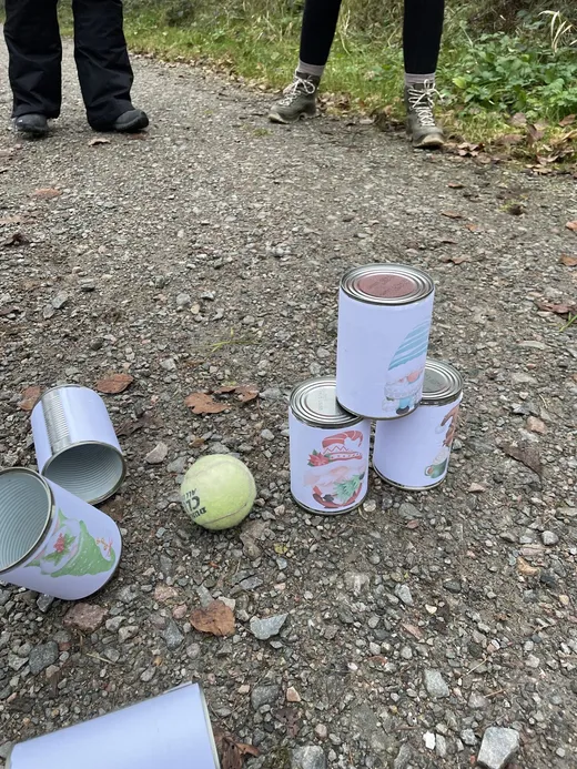 Dosenwerfen-Station einer Schnitzeljagd mit bedruckten Dosen und Ball